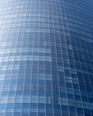 Modern office building facade. Tall business center with a glass facade. Construction of a glass facade structure. The glare of the sun on the glass wall of a skyscraper