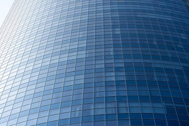 Modern office building facade. Tall business center with a glass facade. Construction of a glass facade structure. The glare of the sun on the glass wall of a skyscraper
