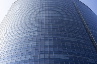Modern office building facade. Tall business center with a glass facade. Construction of a glass facade structure. The glare of the sun on the glass wall of a skyscraper