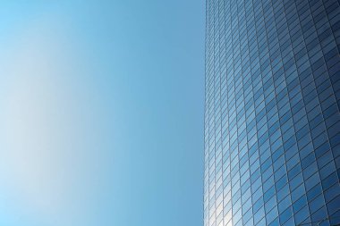 Modern office building facade. Tall business center with a glass facade. Construction of a glass facade structure. The glare of the sun on the glass wall of a skyscraper