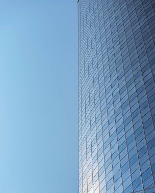 Modern office building facade. Tall business center with a glass facade. Construction of a glass facade structure. The glare of the sun on the glass wall of a skyscraper