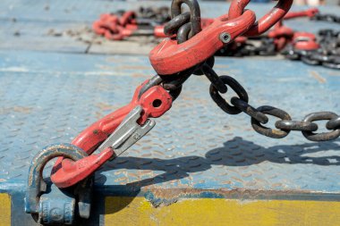 Crane hook, on which chains with hooks and fastening elements are attached. Lifting mechanism in production and warehouse close-up.
