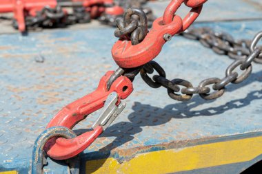 Crane hook, on which chains with hooks and fastening elements are attached. Lifting mechanism in production and warehouse close-up.
