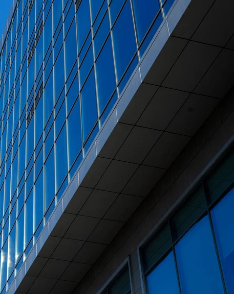 Modern office building facade. Tall business center with a glass facade. Construction of a glass facade structure. The glare of the sun on the glass wall of a skyscraper
