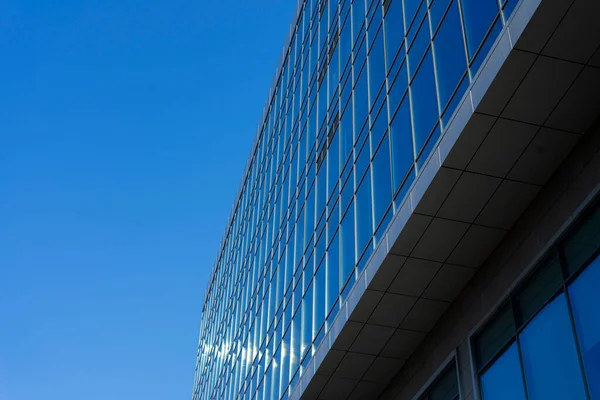 Modern office building facade. Tall business center with a glass facade. Construction of a glass facade structure. The glare of the sun on the glass wall of a skyscraper