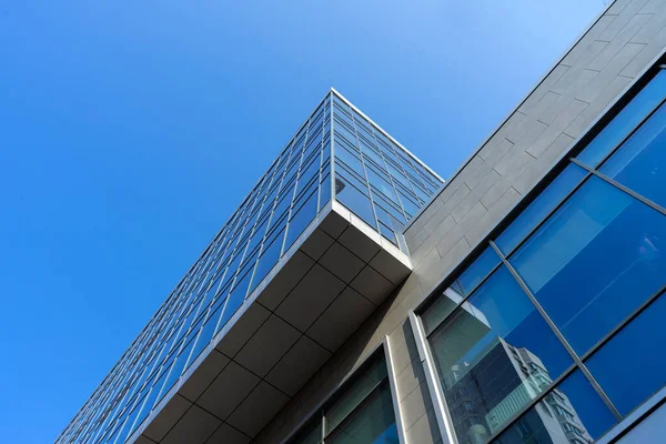 Modern office building facade. Tall business center with a glass facade. Construction of a glass facade structure. The glare of the sun on the glass wall of a skyscraper