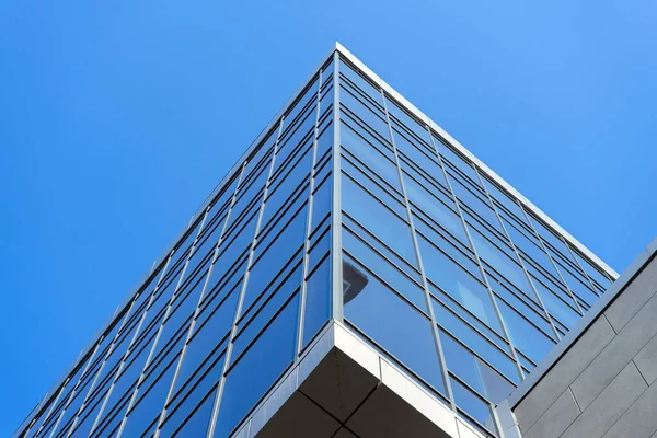 Modern office building facade. Tall business center with a glass facade. Construction of a glass facade structure. The glare of the sun on the glass wall of a skyscraper