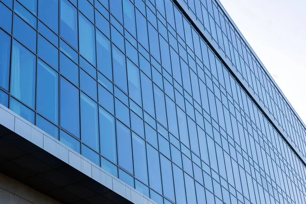 Modern office building facade. Tall business center with a glass facade. Construction of a glass facade structure. The glare of the sun on the glass wall of a skyscraper