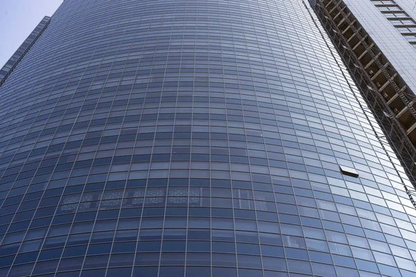 Modern office building facade. Tall business center with a glass facade. Construction of a glass facade structure. The glare of the sun on the glass wall of a skyscraper