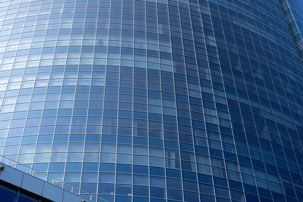 Modern office building facade. Tall business center with a glass facade. Construction of a glass facade structure. The glare of the sun on the glass wall of a skyscraper