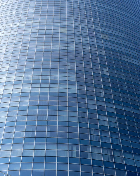 Modern office building facade. Tall business center with a glass facade. Construction of a glass facade structure. The glare of the sun on the glass wall of a skyscraper