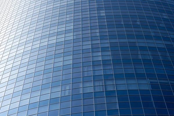 Modern office building facade. Tall business center with a glass facade. Construction of a glass facade structure. The glare of the sun on the glass wall of a skyscraper