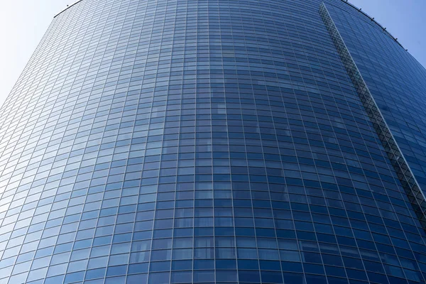 Modern office building facade. Tall business center with a glass facade. Construction of a glass facade structure. The glare of the sun on the glass wall of a skyscraper