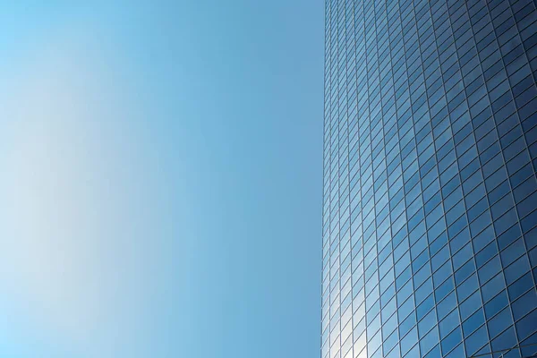 Modern office building facade. Tall business center with a glass facade. Construction of a glass facade structure. The glare of the sun on the glass wall of a skyscraper