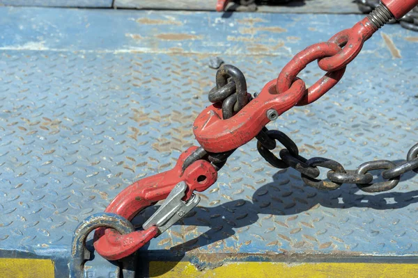 Crane hook, on which chains with hooks and fastening elements are attached. Lifting mechanism in production and warehouse close-up.