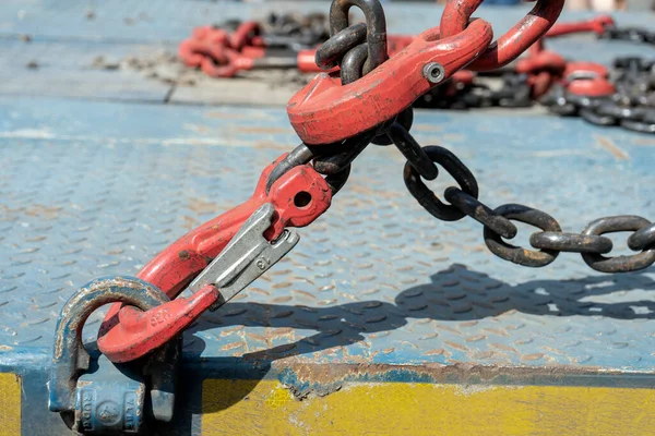 Crane hook, on which chains with hooks and fastening elements are attached. Lifting mechanism in production and warehouse close-up.