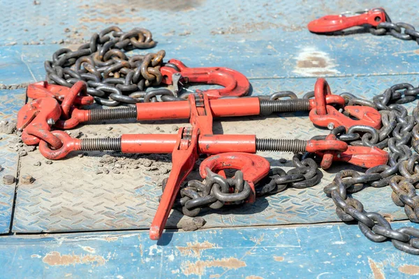 Crane hook, on which chains with hooks and fastening elements are attached. Lifting mechanism in production and warehouse close-up.