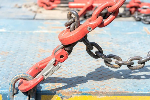 Crane hook, on which chains with hooks and fastening elements are attached. Lifting mechanism in production and warehouse close-up.