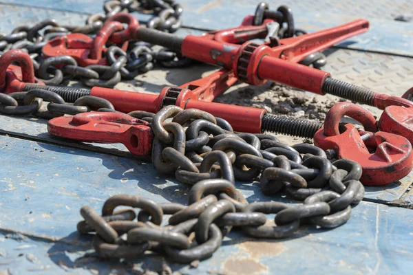 Crane hook, on which chains with hooks and fastening elements are attached. Lifting mechanism in production and warehouse close-up.