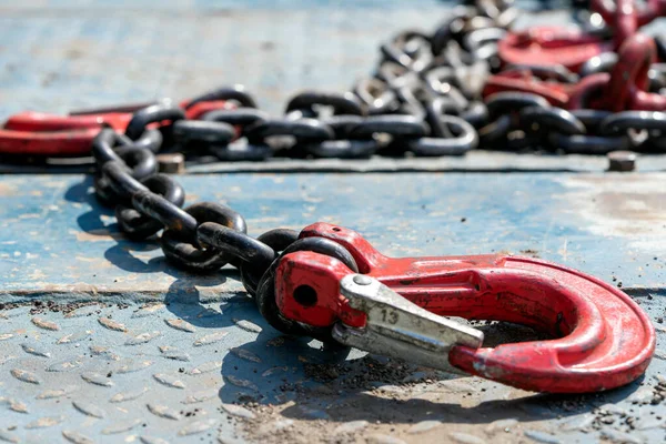 Crane hook, on which chains with hooks and fastening elements are attached. Lifting mechanism in production and warehouse close-up.