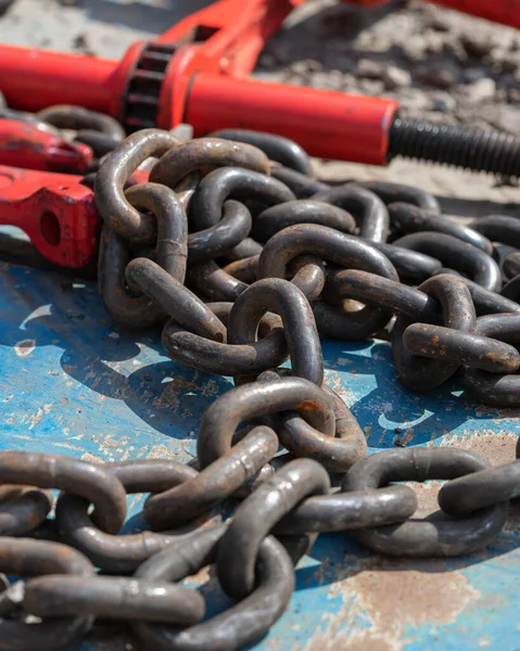 Crane hook, on which chains with hooks and fastening elements are attached. Lifting mechanism in production and warehouse close-up.