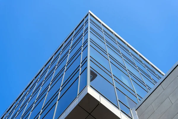 Modern office building facade. Tall business center with a glass facade. Construction of a glass facade structure. The glare of the sun on the glass wall of a skyscraper