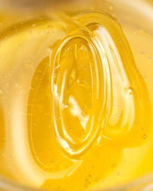 Bal, sarı arka plandaki ahşap bir baldan damlıyor. Tasarımınız için tatlı arı ürünü. Yakın plan.