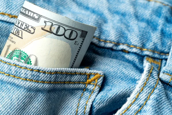 Paper money peeking out of a denim pants pocket. Elements of dollar banknotes close-up. Money, US dollar bills background. . Photo for finance and economy concepts.