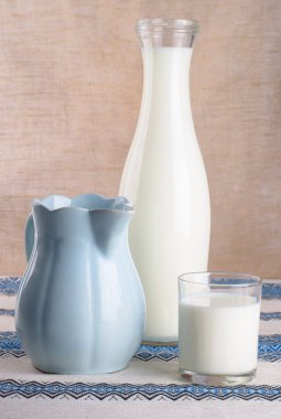 bir bardak süt, bir sürahi ve bir şişe masanın üzerinde