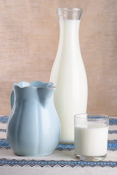 bir bardak süt, bir sürahi ve bir şişe masanın üzerinde
