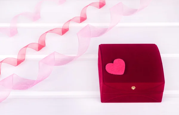 kalp ve şerit beyaz masa üzerinde kırmızı kadife hediye kutusu