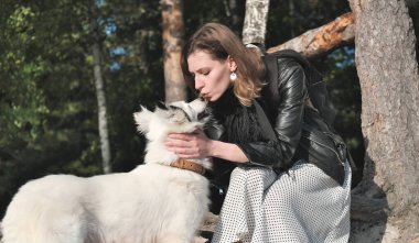 Genç bir kadın köpeği Yakutian Laika 'yı öpüyor. Evcil hayvanlara ve sevgi dolu arkadaşlıklara bayılırım. Kırsalda bir ormanda birlikte yürüyoruz. köpek sadakati
