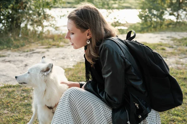 Happy woman hugging and stroking her dog. yakutian laika looking aside. animal friends, outdoor activity and pet care — Stock Photo, Image