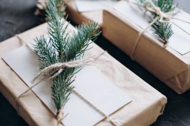 Hediyelerin asgari Noel paketi. Kağıt hazır dekor. Gri arka planda doğal köknar ağacı süslemesi olan ekolojik hediyeler