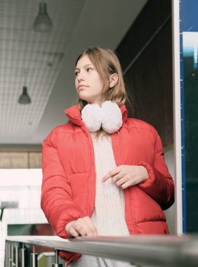 Metro istasyonunda kırmızı ceket ve kulaklık takan güzel bir genç kız. Yalnız yürümek, şehir hayatı. Kasabada genç bir kız