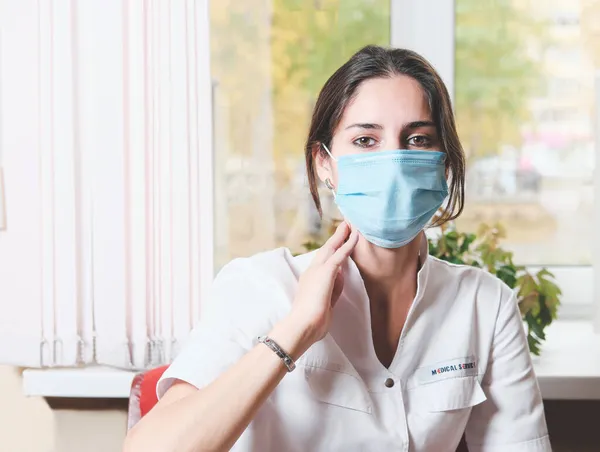 Przemyślana Kobieta Lekarz Noszący Maskę Twarzy Siedzi Przed Oknem Klinice — Zdjęcie stockowe