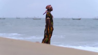 Keta Gana Batı Afrika 'nın tropikal kesiminde puslu bir günbatımında sahilde yürüyen Afrikalı kadın.