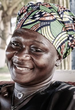 Umut dolu gülümseyen ve geleneksel başlıklı Afrikalı kadın Takoradi Gana, Batı Afrika 'nın tropikal bölgesinde oturuyor.