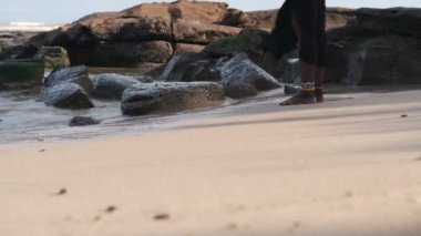 Takoradi Gana Batı Afrika 'nın tropikal kesiminde gün batımında sahilde yürüyen Afrikalı bir kadın.