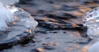 Winter time with running water between ice and snow during sunset in the Swedish valley river