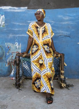 African woman with yellow dress standing by a small soccer goal in Accra Ghana West Africa