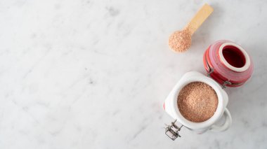 Fotokopi Uzayı ile kaplı mermer bir yüzeyde bulunan kavanozdaki Pembe Himalaya Tuzu