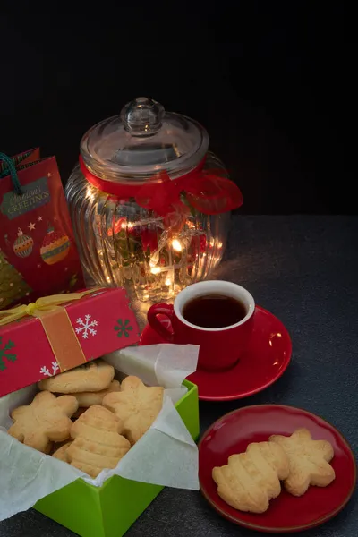 コピースペースで暗い背景に紅茶とクリスマスライトとクリスマスのショートブレッドギフト垂直 — ストック写真
