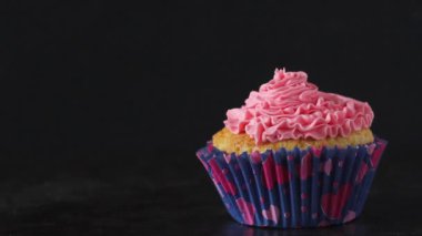 Koyu arka plan üzerinde dağınık kalp Sprinkles ile pembe Buttercream Frosting ile tek vanilyalı kek