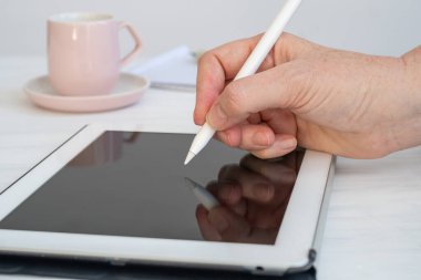 Arka planda kahve ve not defteriyle masadaki tablete yazmak için Dijital Kalem kullanan Yakın Çekim Kadını