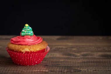 Individual Christmas Cupcake with Christmas tree Topper on Dark Background with Copy Space