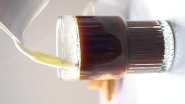Milk Being Poured onto Large Coffee Glass on Light Background Vertical Footage Slow Motion