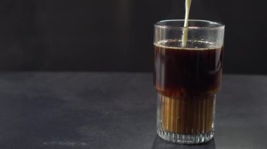 Milk Being Poured onto Large Coffee Glass on Dark Background with Copy Space