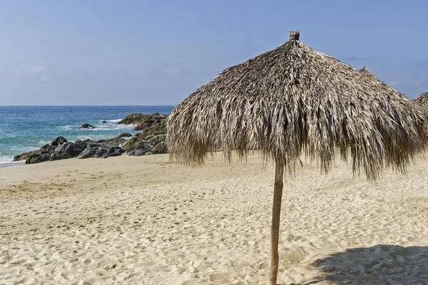 Sombrilla de playa de paja por el océano — Foto de Stock