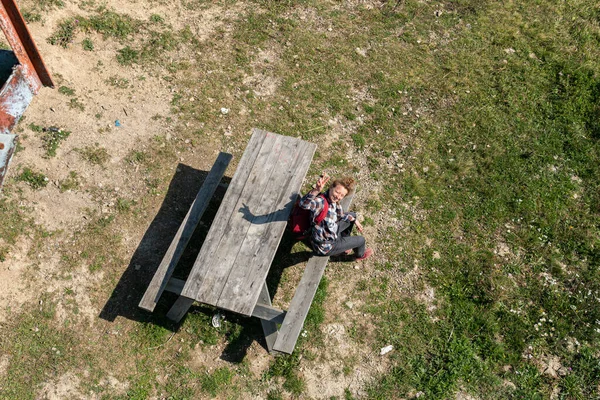 在阳光灿烂的夏天 一位年轻女子正坐在桌旁的木制长椅上 在山顶上休息 — 图库照片